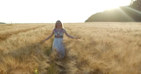 Cheerfully running and spinning round young blonde girl along the golden wheat Stock Footage 84806434