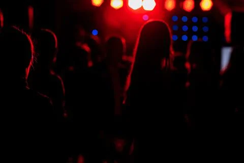 Cheering crowd in front of bright red stage lights. Silhouette image of peopl Stock Photos