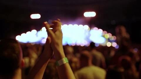 Cheering hands at a concert in front of a large stage in the spotlight close-up Stock Footage 227511479