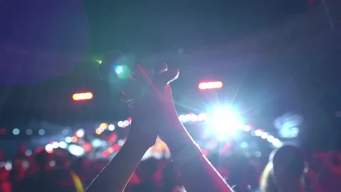 Cheering hands at a concert in front of a large stage in the spotlight close-up Stock Footage 229806264