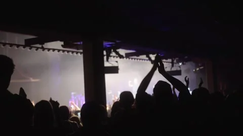 Cheering hands at a concert in front of a large stage in the spotlight close-up Stock Footage 270059148