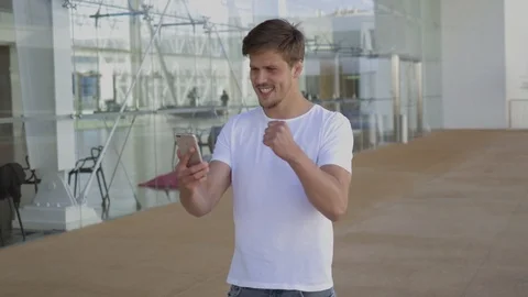 Cheering young man looking at smartphone. Video stock 106679325