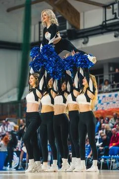 Cheerleader doing a split while other girls holding her up in the air on the Stock Photos