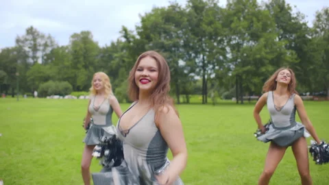 A cheerleader shakes her pom-poms smiles and encourages action