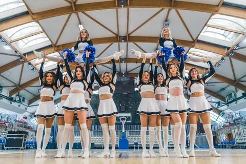 Cheerleaders doing a split while other girls holding them up in the air on the Stock Photos