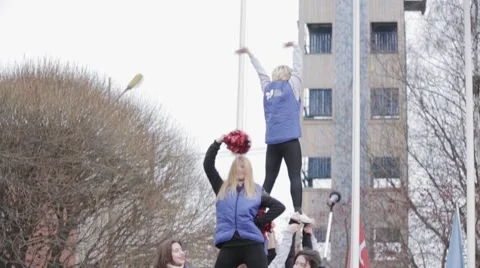 Cheerleaders in jackets make acrobatic elements on stage. Red shakers. Outdoor 库存影片 60404585