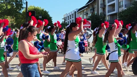 Cheerleaders marching in parade with red and blue pom poms 動画素材 340941601
