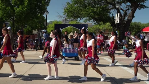 Cheerleaders marching in parade wearing red and white uniforms 動画素材 340940936