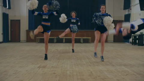 Cheerleaders practicing using pom poms and guy doing handstand Stock Footage 279750648