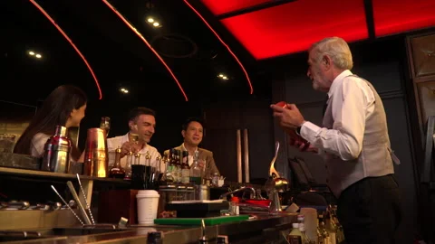 Cheers . senior man bartender standing at bar counter talking with customer a Stock Footage 144996597