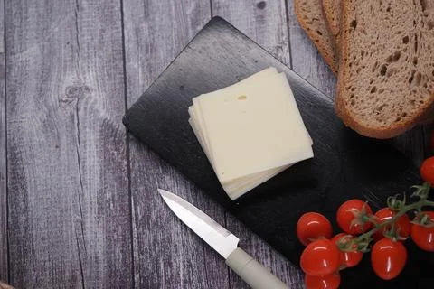Cheese and bread on a black board with cherry tomatoes Stock Photos