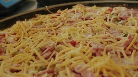 Cheese and meat toppings on a pizza ready for baking in a kitchen Stock Footage 345203151