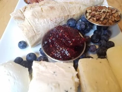 Cheese and pecans and bread and blueberries on white plate Stock Photos