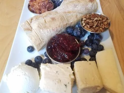 Cheese and pecans and bread and blueberries on white plate Stock Photos