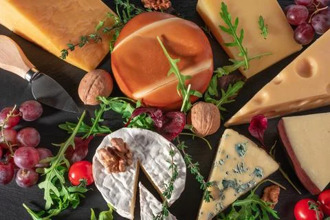 Cheese background. Assortment different types of cheese with walnuts, tomato  Stock Photos