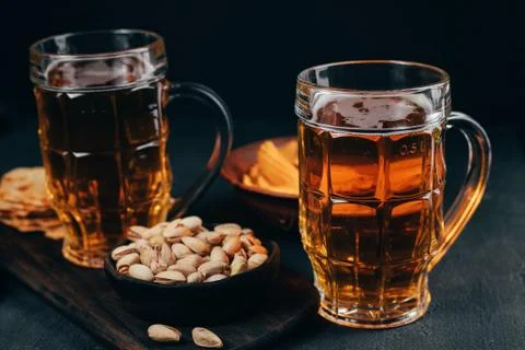 Cheese balls and nuts with two mugs of light beer Stock Photos