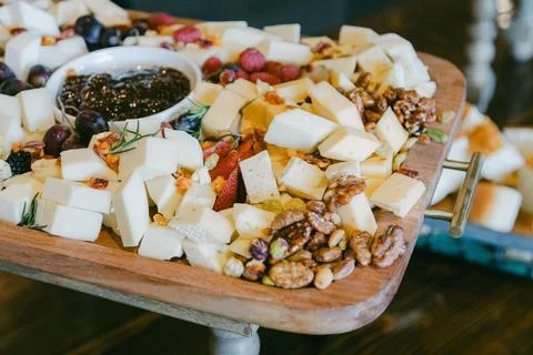 Cheese board with assorted cheeses, nuts, and fruits displayed at an event in a Foto stock