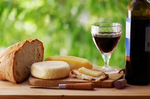 Cheese, bread, and red wine on table Foto stock