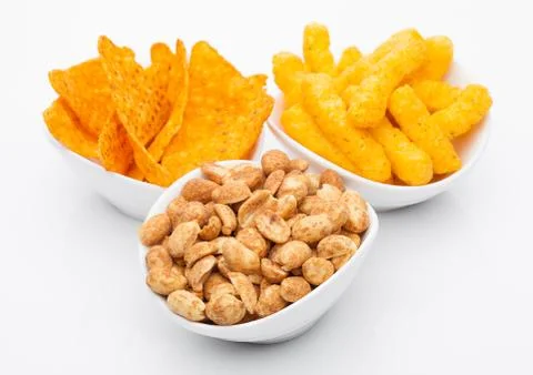 Cheese corn snacks and nachos with salty peanuts in white bowl Stock Photos