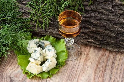 Cheese cubes on a lettuce leaf with a stack of cognac on the background of tr Stockfoto's