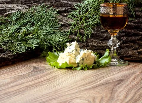 Cheese cubes on a lettuce leaf with a stack of cognac on the background of tr Stockfoto's