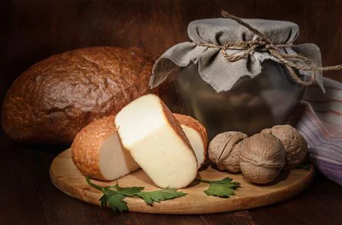 Cheese on a cutting board in a rustic style on a dark wooden background Stock Photos