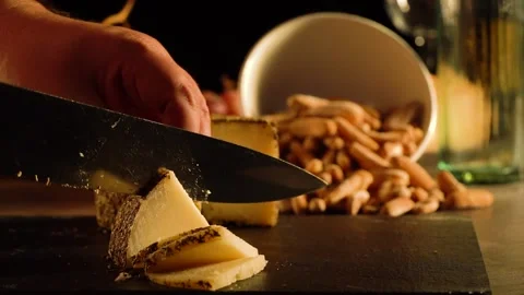 Cheese cutting process with herbs on a dark board with a bowl of breadsticks. Stock Footage 169995753