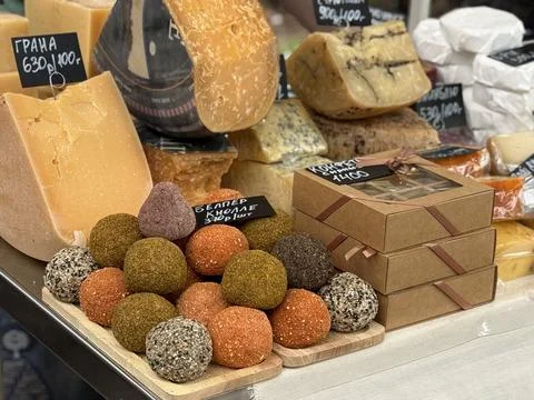 Cheese display with various hard cheeses and colorful cheese balls at a mar.. 库存照片