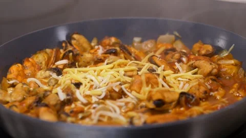 Cheese falling into hot pan filled with mussels in tomato sauce, gentle steam Stock Footage 321818285
