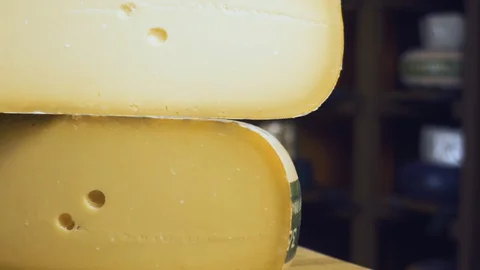 Cheese gouda lies on the table. Next lies a knife for cheese. On the shelves is Stock Footage 89007633