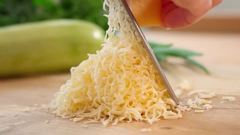 Cheese is grated on a wooden board using a fine grater. Close-up Stock Footage 253876032