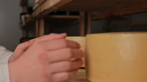 A cheese maker adjusts a head of cheese on a shelf Vidéo 180041307