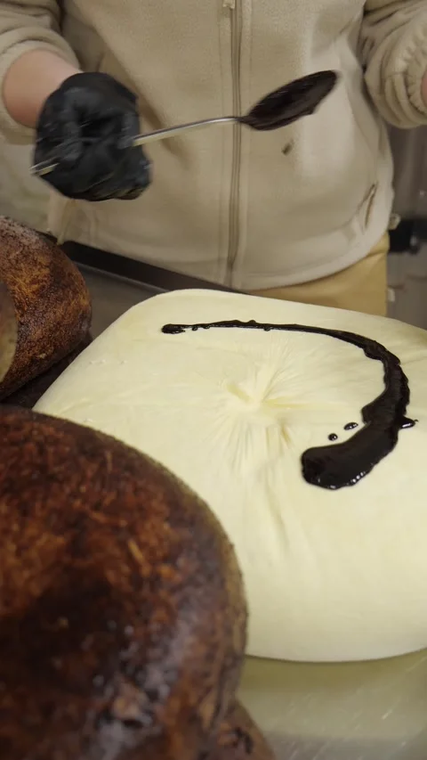 Cheese Maker Applying Dark Coating to Large Cheese Wheel50 Видео 342542045