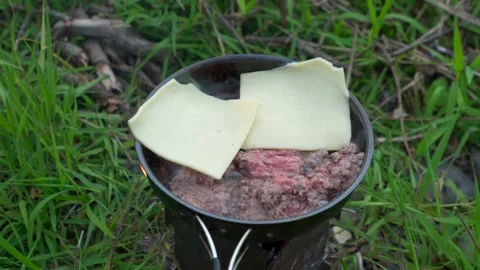 Cheese melting onto beef in a frying pan outdoors Video stock 246746995