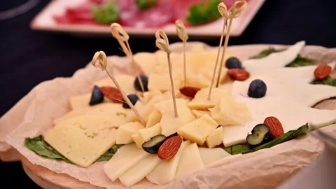 Cheese platter with assorted cheeses, nuts, and fruits on wooden board Stock Footage 340411612