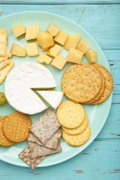 Cheese platter with different cheese and crackers on mint background. Stock Photos