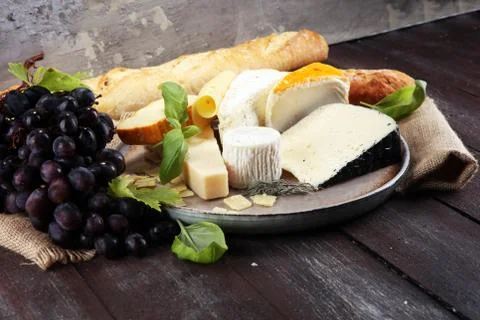 Cheese platter with different cheese on rustic plate. Stock Photos