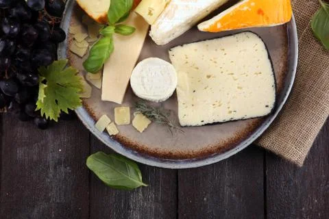 Cheese platter with different cheese on rustic plate. Stock Photos