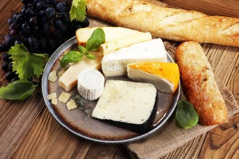 Cheese platter with different cheese on rustic plate. Stock Photos