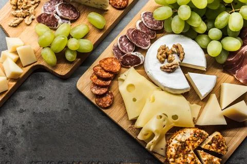 Cheese platter with different types of cheese, salami and grapes Stock Photos