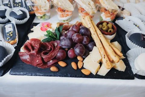 Cheese platter features assorted meats, grapes, almonds, and breadsticks Foto stock