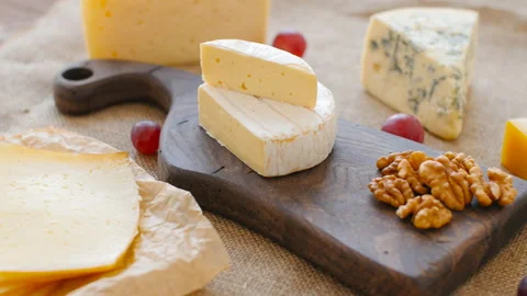 Cheese platter with nuts and grapes on a wooden cutting board Stock Footage 98315419
