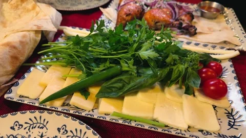 A cheese platter is served with fresh lavash bread, herbs, and vegetables. Next Video stock 330796380