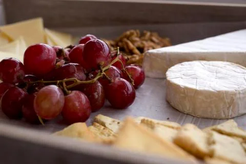 Cheese platter served with grapes, nuts and bread. Side view of cheese still Stock Photos
