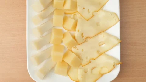 Cheese platter with various sliced types arranged on white tray Stock Footage 348308032
