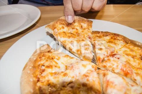 Cheese reaches for a piece of freshly baked hot pizza, someone's hand pulls o Stock Photos