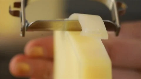 Cheese is scraped into Strips with Cheese Scraper Slowmotion Closeup Stock Footage 99198224
