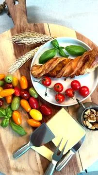 Cheese slice, breadstick, fresh cherry tomatoes, colorful mixed tomatoes, basil Stock Photos