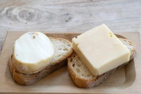 Cheese slices on rustic bread tray Stock Photos