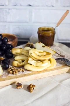 Cheese string, honey, grapes, pears and nuts on wooden board on kitchen Stock Photos